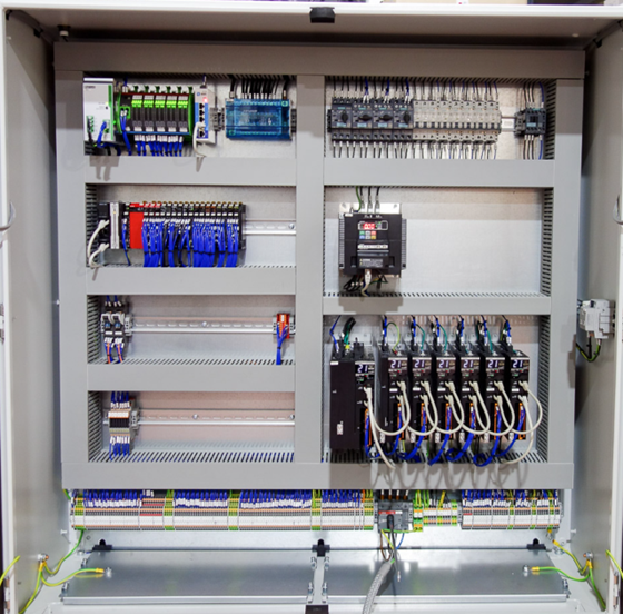 Industrial control panel with PLC modules, servo drives, contactors and wired terminal blocks inside an enclosure.